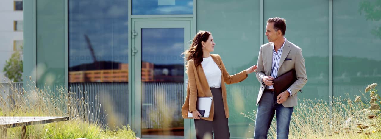Two people walking through a kitchen area.