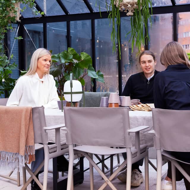 People sitting around a table in a greenhouse.